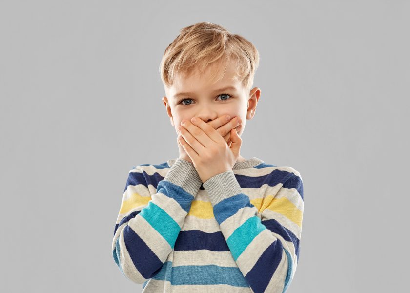 shocked little boy closing his mouth by hands
